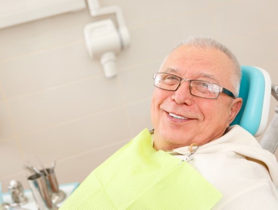 Senior man smiling in dental chair after dental implant salvage in Rocky Hill
