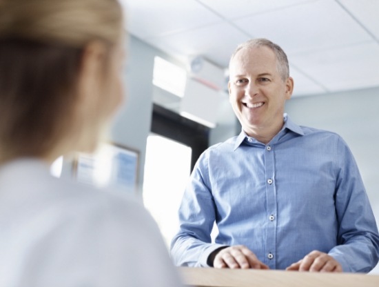 Man smiling at dental office receptionist