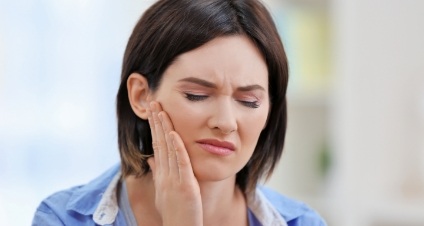 Woman winning and holding her jaw in pain