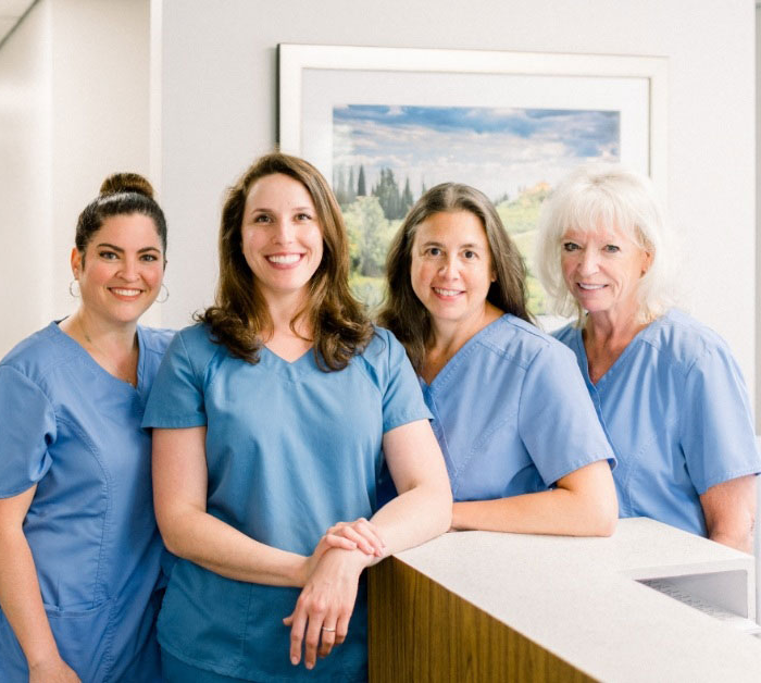 Smiling Rocky Hill dental team members in front of front desk