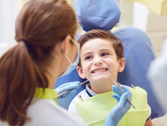 Young boy in dental chair smiling at his dentist
