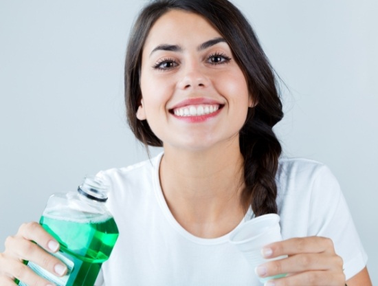 Smiling woman holding bottle of mouthwash