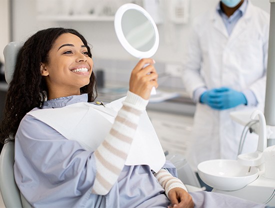 Happy dental patient, holding mirror and smiling