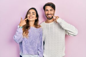 Happy, smiling couple pointing at their teeth 